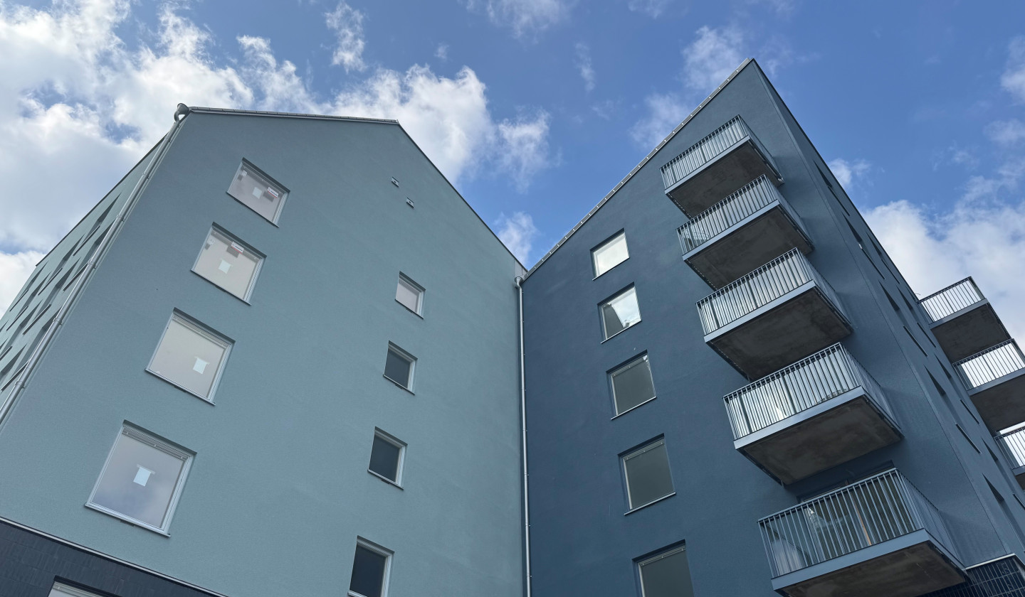 Detaljbild på fasaden på en byggnad i kv Målburen 1. Fastigheten i blå nyanser tornar upp sig mot den blå himlen.