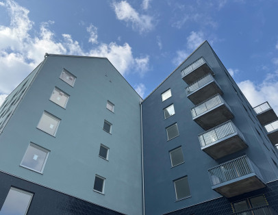 Detaljbild på fasaden på en byggnad i kv Målburen 1. Fastigheten i blå nyanser tornar upp sig mot den blå himlen.