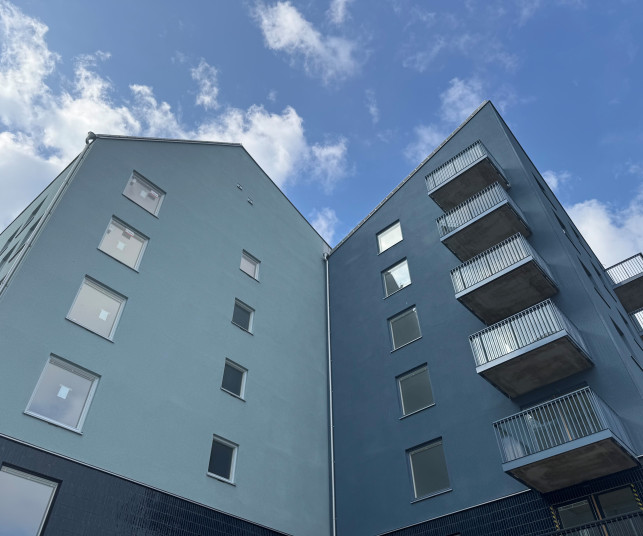 Detaljbild på fasaden på en byggnad i kv Målburen 1. Fastigheten i blå nyanser tornar upp sig mot den blå himlen.