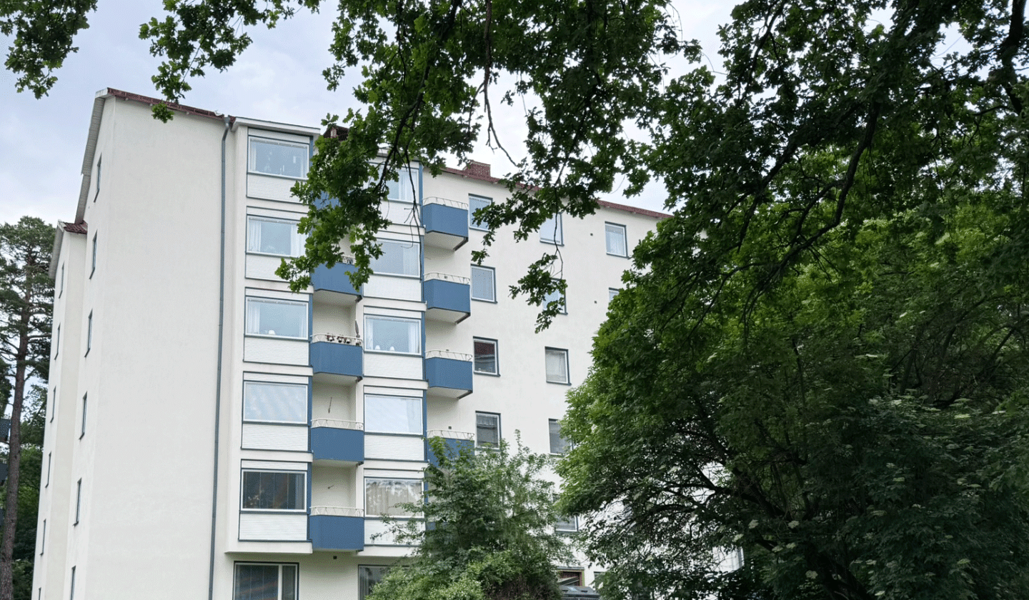 Fastigheten skymtar bakom träd och buskar.