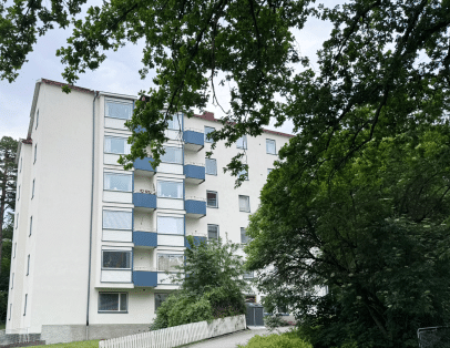Fastigheten skymtar bakom träd och buskar.